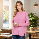 Model wearing a pink RELAX MODE TOP (taffy), showcasing its soft fabric and relaxed fit, holding a cup in a cozy setting.