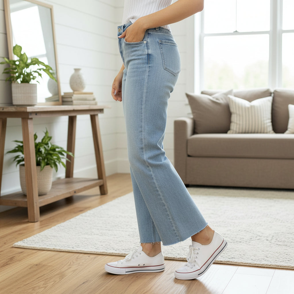 Woman wearing ZELDA WIDE LEG JEANS by Vervet in a stylish living room, showcasing the high-rise waist and raw hem.