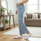 Woman wearing ZELDA WIDE LEG JEANS by Vervet in a stylish living room, showcasing the high-rise waist and raw hem.