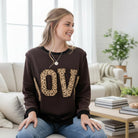 LOVE UNTAMED TOP - Easel worn by a model, featuring leopard print letters on a comfy dark top.