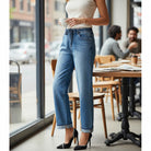 DARCY JEANS by Risen worn by a woman in a cafe, featuring elastic waist and relaxed wide leg style with cuffed hem.