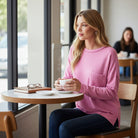Woman sipping coffee while wearing the RELAX MODE TOP (taffy) in a cozy cafe setting.