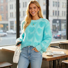 LOVE AT FIRST SIGHT SWEATER worn by a smiling woman in a cozy café, featuring heart pattern and fuzzy texture.