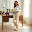 Woman wearing COMFORT CULTURE PANTS (cream) with leopard drawstring, cozy fleece-lined interior, in a bright office.