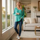COZY CONCEPTS RIBBED TOP (turquoise) worn by a woman, showcasing relaxed style in a sunlit living room.