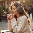 C.C. Sherpa Earmuffs (3 colors) worn by a woman enjoying a warm drink in a cozy outdoor setting.