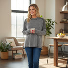 MAIN STREET MOMENTS Top (espresso) worn by a smiling woman holding a mug in a cozy, modern living area.
