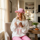SOFTLY TIED CREWNECK in a cozy setting, model wearing a bowknot pattern top with a pink cap, enjoying a warm drink.