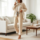 A woman wearing Comfort Culture Pants (cream) with leopard drawstring, cozy and stylish in a home setting.
