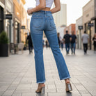 Woman wearing FAE JEANS by Risen, showcasing high-rise flare leg and frayed hem in a casual outdoor setting.