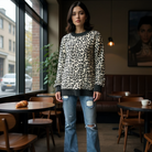 A woman wearing THE PERFECT SPOT Ribbed Top with snow leopard print, styled casually in a cafe setting.