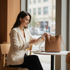Woman enjoying coffee with POLISHED PATH HANDBAG (cinnamon) in vegan leather at a stylish cafe.