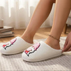 HUGS & HEARTS SLIPPERS featuring a fluffy white design with an embroidered character in a pink hat and hot pink pants.