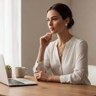 Model wearing LOVE STORY Earrings and Necklace Set (silver) while working at a desk with laptop and cup of coffee.