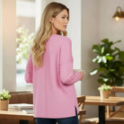 Woman wearing the RELAX MODE TOP (taffy) in a cozy cafe setting, showcasing its relaxed fit and soft fabric.