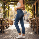 Model showcasing YARA JOGGERS by Risen Denim in a sunny outdoor cafe setting, highlighting the stylish fit and comfort.