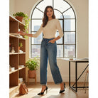 DARCY JEANS by Risen worn by a woman standing in a stylish office, flaunting relaxed fit wide leg jeans and elegant heels.