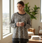 THE PERFECT SPOT Ribbed Top in snow leopard print, model holding a cup in a cozy setting.