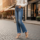 Model wearing FAE JEANS by Risen, high-rise flare jeans with frayed hem in a stylish urban setting.