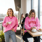 DOUBLE THE LOVE REVERSIBLE PULLOVER in bright pink with heart and LOVER graphics, showcased by models.