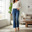 Model wearing ALIZA JEANS by Risen, showcasing high-rise flare patch pocket denim in a stylish living room setting.