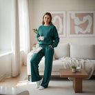LAKEHOUSE LUXE PANTS SET featuring a woman in sea teal textured sweatshirt and high-waist pants, relaxing with a mug.