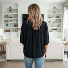 FIERCE FOCUS TOP in black featuring dolman half sleeves, perfect for a stylish and relaxed look in a modern living room.