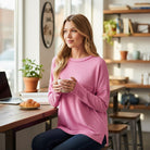 Woman enjoying coffee while wearing the RELAX MODE TOP (taffy) in a cozy café setting.