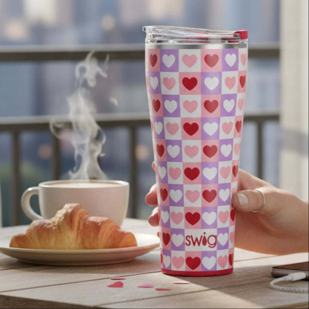 CHECK YES TUMBLER- SWIG with heart design, 32oz standing beside a steaming cup and croissant.