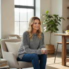 Woman enjoying coffee in a cozy space, wearing a MAIN STREET MOMENTS Top (espresso) and jeans.
