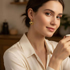 Woman wearing FOREVER YOURS EARRINGS, showcasing their heart shape and 18K gold-plated finish.