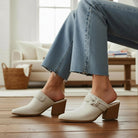 HAZEL SLIP-ON MULES in white with knotted strap, paired with blue jeans, showcasing a stylish and comfortable design.