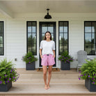 Model wearing BXGH-PINK GINGHAM BOXER SHORTS with a white tee on a porch surrounded by flower pots.