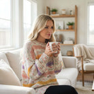 Model wearing EASY LIKE SUNDAY SWEATER while enjoying a warm drink in a cozy living room.