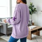Back view of a woman wearing a lavender MARDI GRAS STAR PULLOVER with sequined star patch.