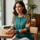 Model wearing HIGHLAND RETREAT TOP in a cozy café setting, enjoying coffee and radiating stylish comfort.