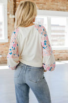 Back view of the VANILLA SKYE TOP, featuring floral patchwork balloon sleeves and a lightweight design in a stylish setting.