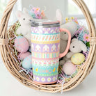 BUNNY TRAIL 22 OZ TRAVEL MUG - Swig Life in a basket surrounded by Easter eggs and plush bunnies.